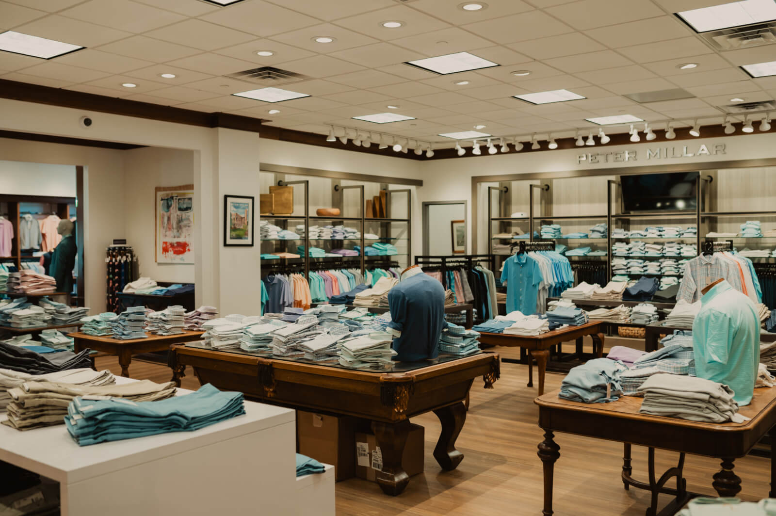 Oak Hall men’s clothing store interior with neatly folded shirts and polos on tables and shelves, bright lighting, and organized displays of casual wear.