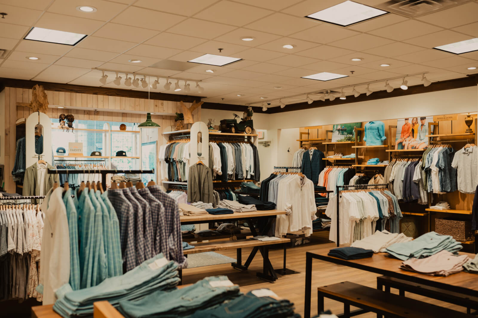 Oak Hall clothing store interior with neatly arranged racks and shelves displaying shirts, pants, and accessories under bright ceiling lights.