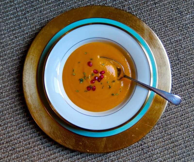 The velvety smooth texture of this creamy pumpkin soup is complemented by the crunch of a pomegranate seed garnish.
