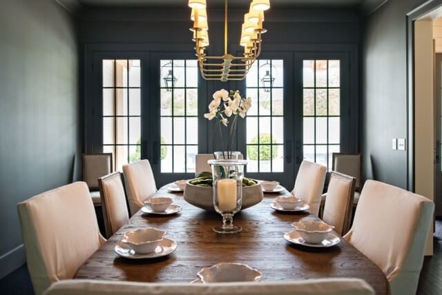 The deep, gray walls add an unexpected panache to the design. White upholstered chairs are the perfect accent. 