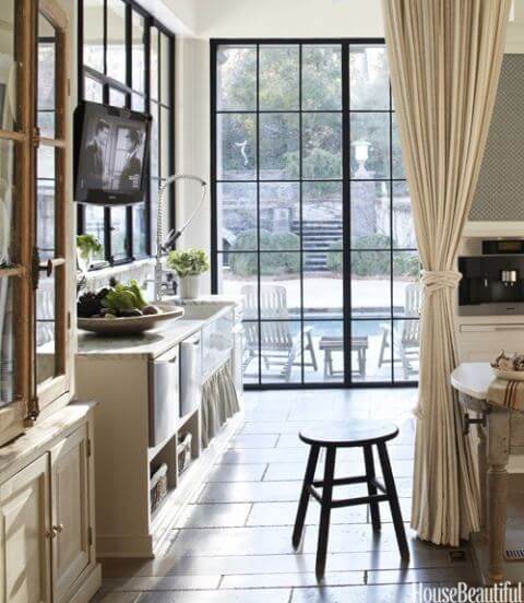 Floor-to-ceiling glass and steel windows overlooking a pool area