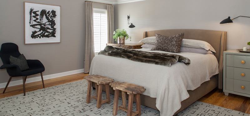 The master bedroom is one of the home's best examples of modern rustic charm. Carved wooden footstools and traditional neutrals are in healthy competition with modern furnishings and an abstract painting by David Nestor from the L Ross Gallery. | Image credit: Julie Wage Ross