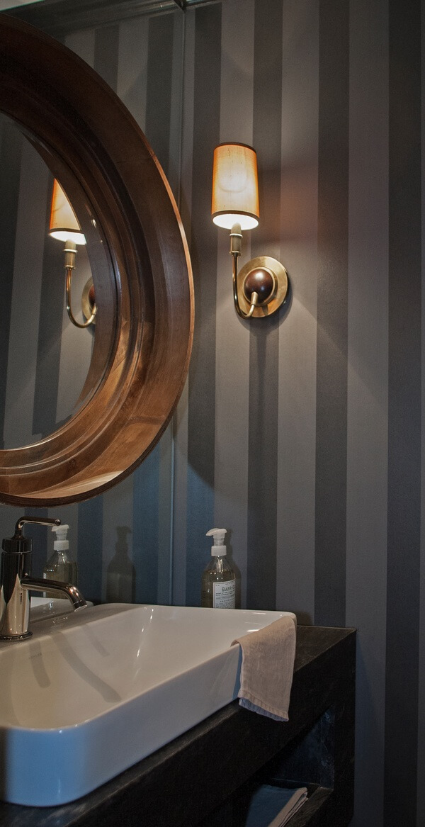 Where space is limited, there are ways to totally trick the eye into seeing a bigger area. In a downstairs powder room, a plate glass mirrorwas used in lieu of a backsplash to make space feel larger. | Image credit: Julie Wage Ross