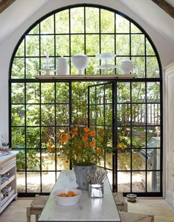 Arched window with glass and steel doors makes for a dramatic entrance to the back patio from the kitchen. Just one of many steel and glass windows featured today!