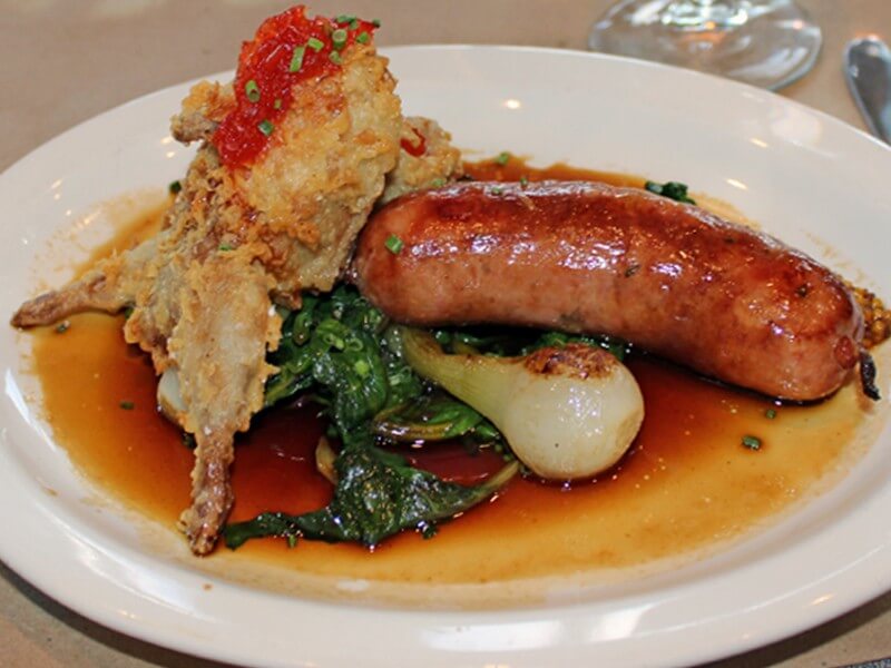 The Sportsman is a wild game repast that changes with the seasons. Featured here is fried quail and homemade kielbasa with swiss chard and spring onions.