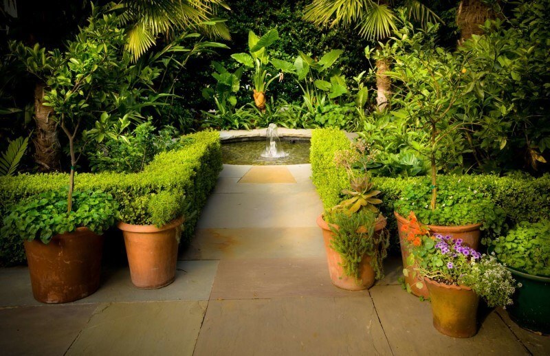Lined by greenery, this shrouded fountain in New Orleans is a hidden paradise. Part of 8 garden fountains featured in this article by StyleBlueprint