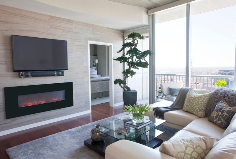An entire wall clad in gray tiles with an electric fireplace for warmth gives the living room a wow factor.