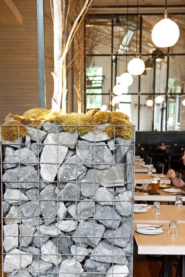 I love how the outdoors comes in with dividers of wire baskets filled with rocks, cross sections of fat tree trunks and arrangements of sticks and moss in box frames