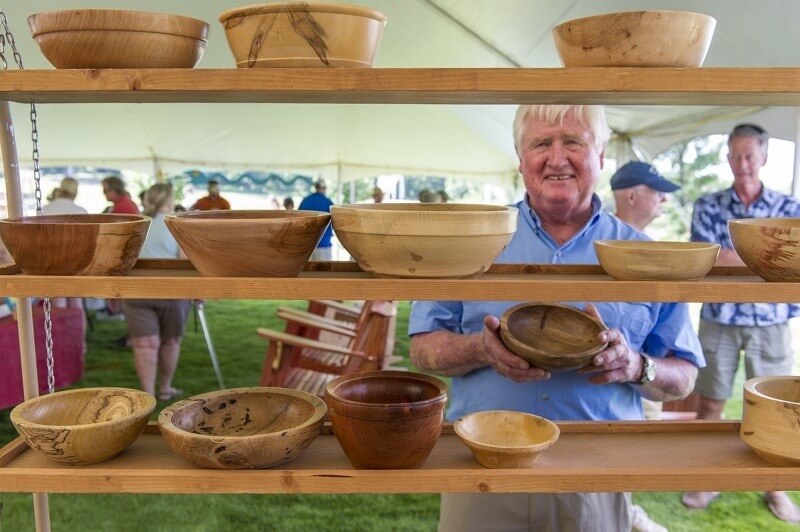a woodworker at the annual, family-friendly Arti Gras festival on the Town Green, featuring wares from local artists and craftsmen