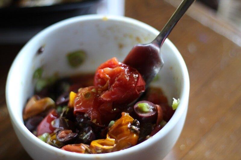 Place the ingredients in a bowl and smash the tomatoes (you may need to use your hands) and mix with the olives and green onions. Add some of the balsamic reduction, garlic powder and kosher salt.