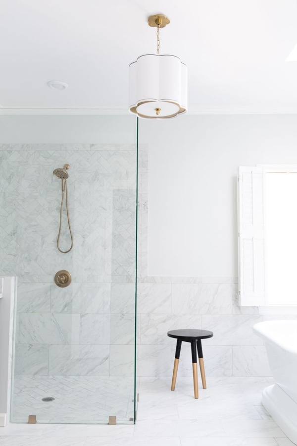 Shower straight on: Tile serves as wainscoting in the bathroom, linking the shower and tub areas. Designer Anna Braund made sure the existing window was kept intact, saying, “It’s imperative to keep as much natural light as you can in your bathroom, since no amount of electricity can replace the warmth of natural light.  If you need privacy, dress your windows with a sheer or shutters that will allow some light to penetrate in the room.”