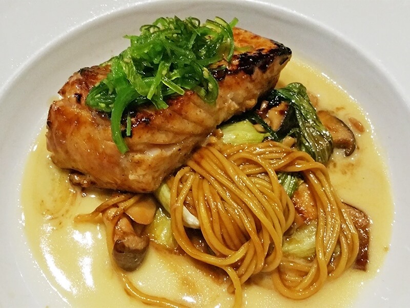 Halibut served on a bed of house-made wasabi tagliatelle pasta with sauteed baby bok toy and golden chanterelle and trumpet mushrooms in a miso-sweet soy buerre blanc