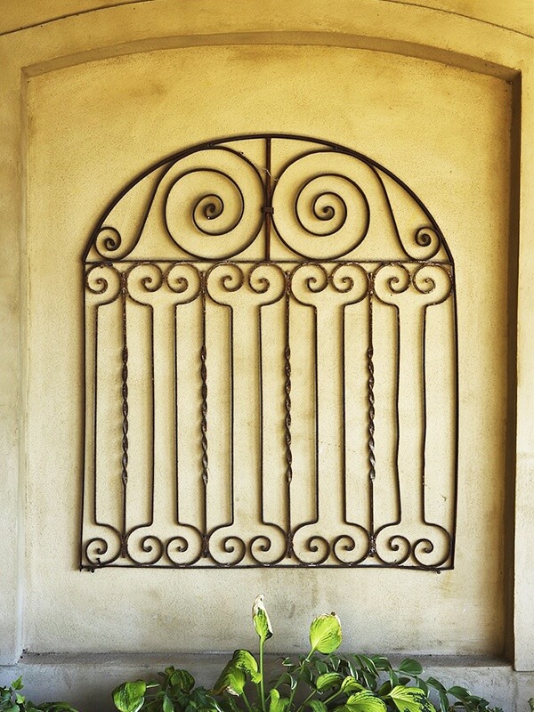 This antique gate is an intriguing art piece that adds a timeworn elegance to the rustic wall of this covered poolside refuge.