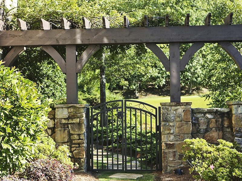 A picturesque stone wall and gate enclose the impressive outdoor spaces of this mountaintop home.