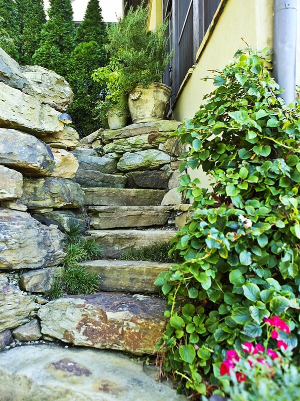 A hand-laid stone walkway curves down from the screened-in porch, the scent of the potted fresh rosemary and basil mingles with the gentle trickling sounds of a nearby waterfall.