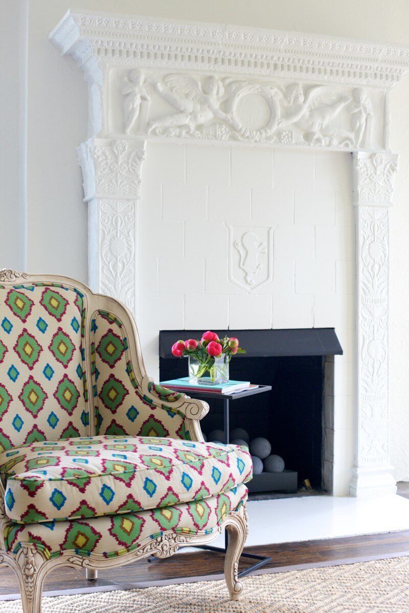 This carved terra cotta fireplace, in a fresh white color palette, needs no centerpiece as its detailed carvings are a stunning standalone statement piece.