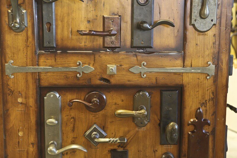 Door hardware mounted to a rustic door in the Brandino Brass showroom