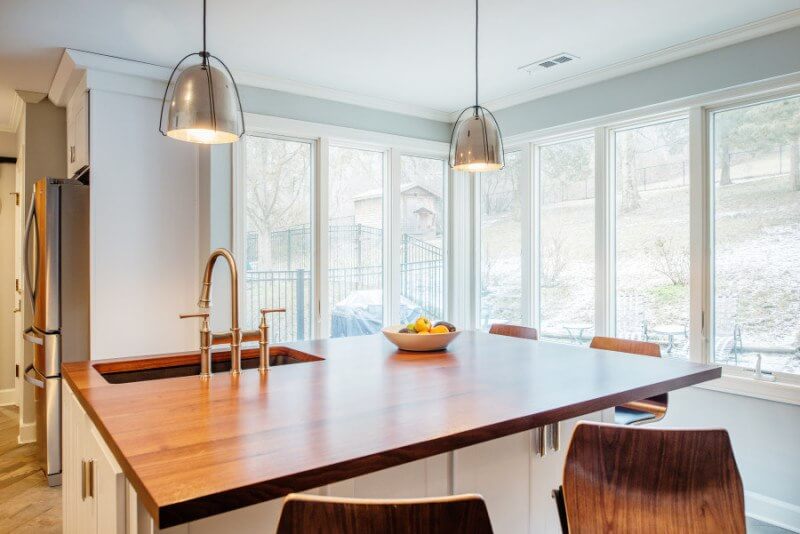 Natural light makes everything better! Open concept kitchen ideas: white kitchen with a wooden countertop.