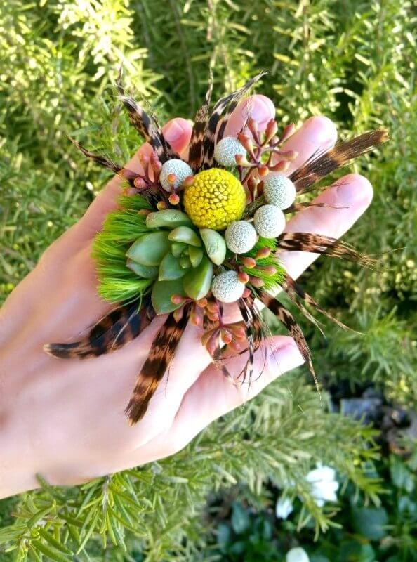 Check out this elegant ring corsage made with: succulent, gold craspedia, green trick dianthus, seeded eucalyptus and pheasant feathers. Find many examples of ring corsages on StyleBlueprint.com
