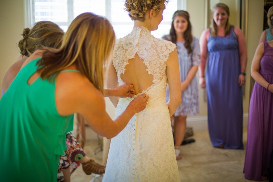 Kayla’s mom and sister help her button up her gown, while Kayla’s bridesmaids tearfully look on.