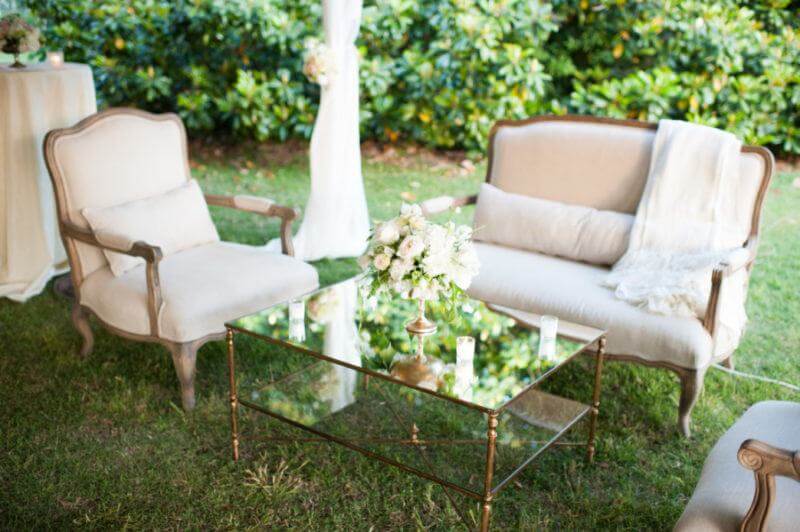 Under a white tent, neutral seating and elegant mirrored gold tables were placed for cozy seating.