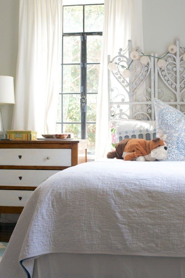 The headboard is simply a rattan screen that Caroline bought for $25 and spray-painted white. 