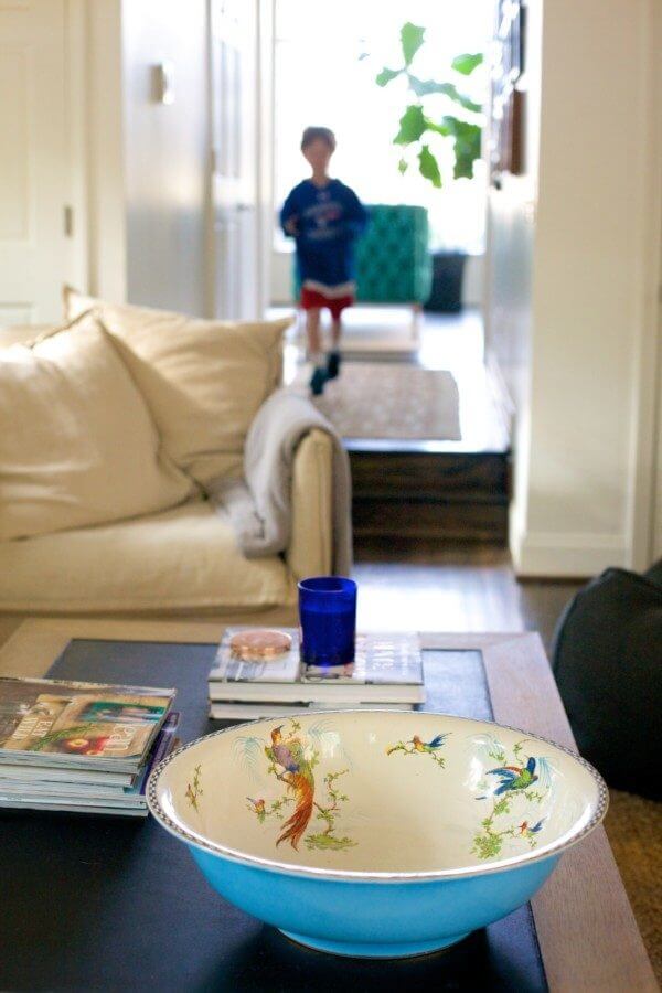One of Caroline's sons runs from "the big room" into the family's den, where one of Caroline's favorite finds, an antique blue bowl from an estate sale, adds a pop of color to the coffee table. 