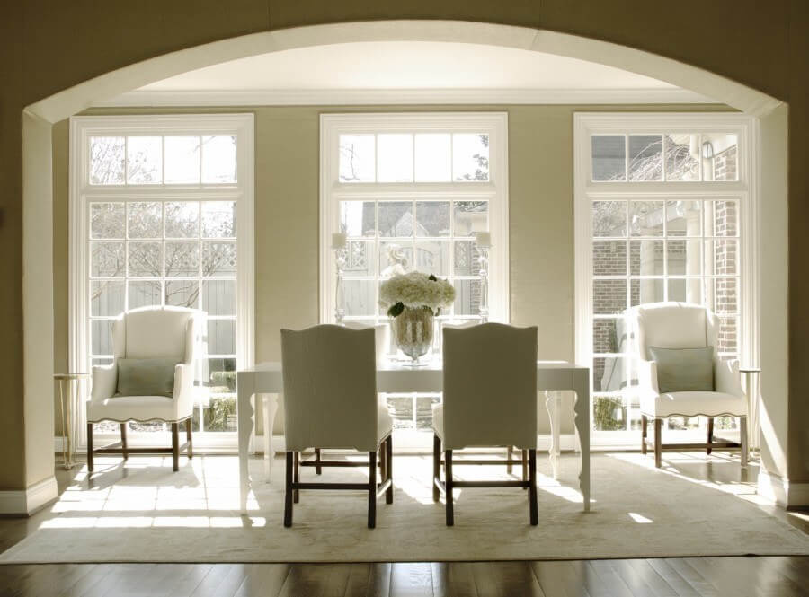 A modern table and large mercury vase mix with more traditional chairs and neutral colors in this light-filled space for a stunning result. Image: Howard Lee Puckett Photography