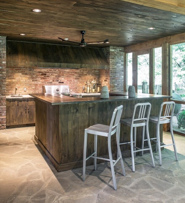 A bar space and outdoor kitchen is tucked into one side of the screened porch, allowing for multiple gathering areas. Image | Julie Wage Ross