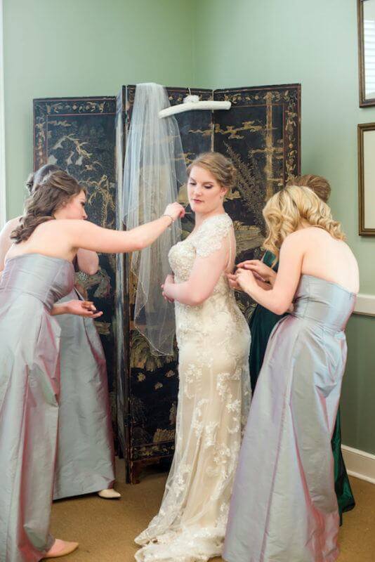 Bridesmaids help put finishing touches on Sarah’s dress