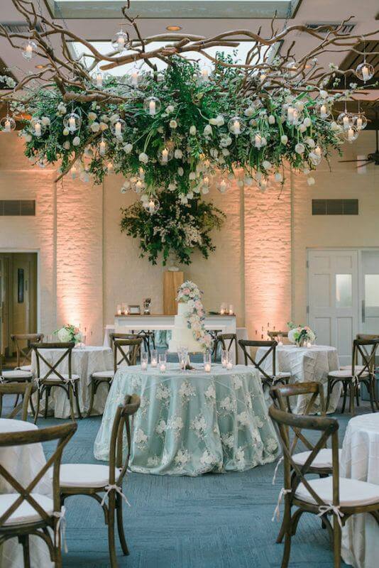 The palette continued into the reception space, where white tulips, branches and greenery hung from the ceiling inside the Hughes Pavillion. These were placed as a subtle nod to the tulip field where Sarah and John got engaged. Cream colored silk tablecloths and natural seating, uplighting and tea candles set the mood indoors. Cafe string lights and white silk tents created an intimate space outdoors.