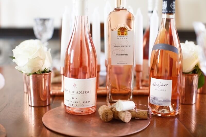 Antique copper trivets and a candelabra set the stage for six to eight centerpiece rosé bottles of different shades and sizes.