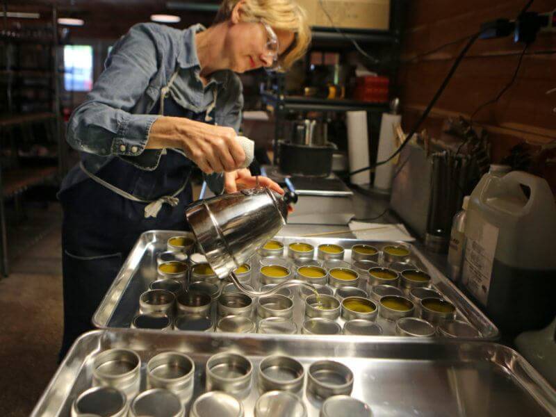 Tins of "Hand Aid" are carefully poured by a Little Seed employee.