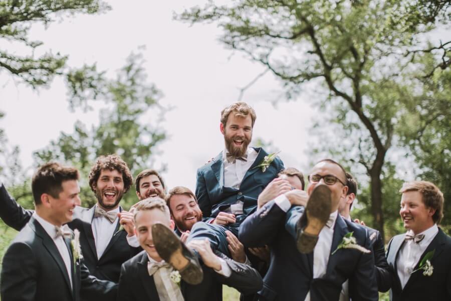 The groomsmen goof off, carrying their champ to the first look.