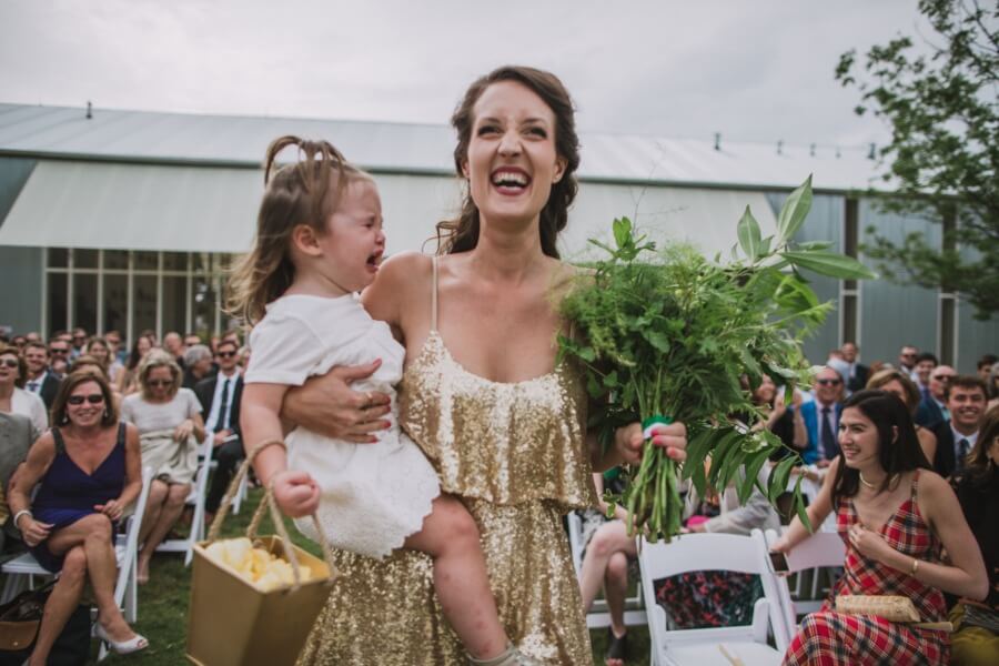 A bridesmaid carries her crying flower girl daughter down the aisle, which made for a comedic moment.