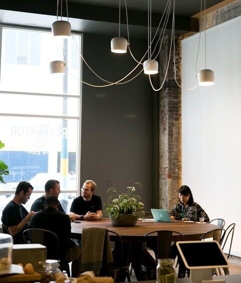 A group meets at the large community table to collaborate and socialize. 