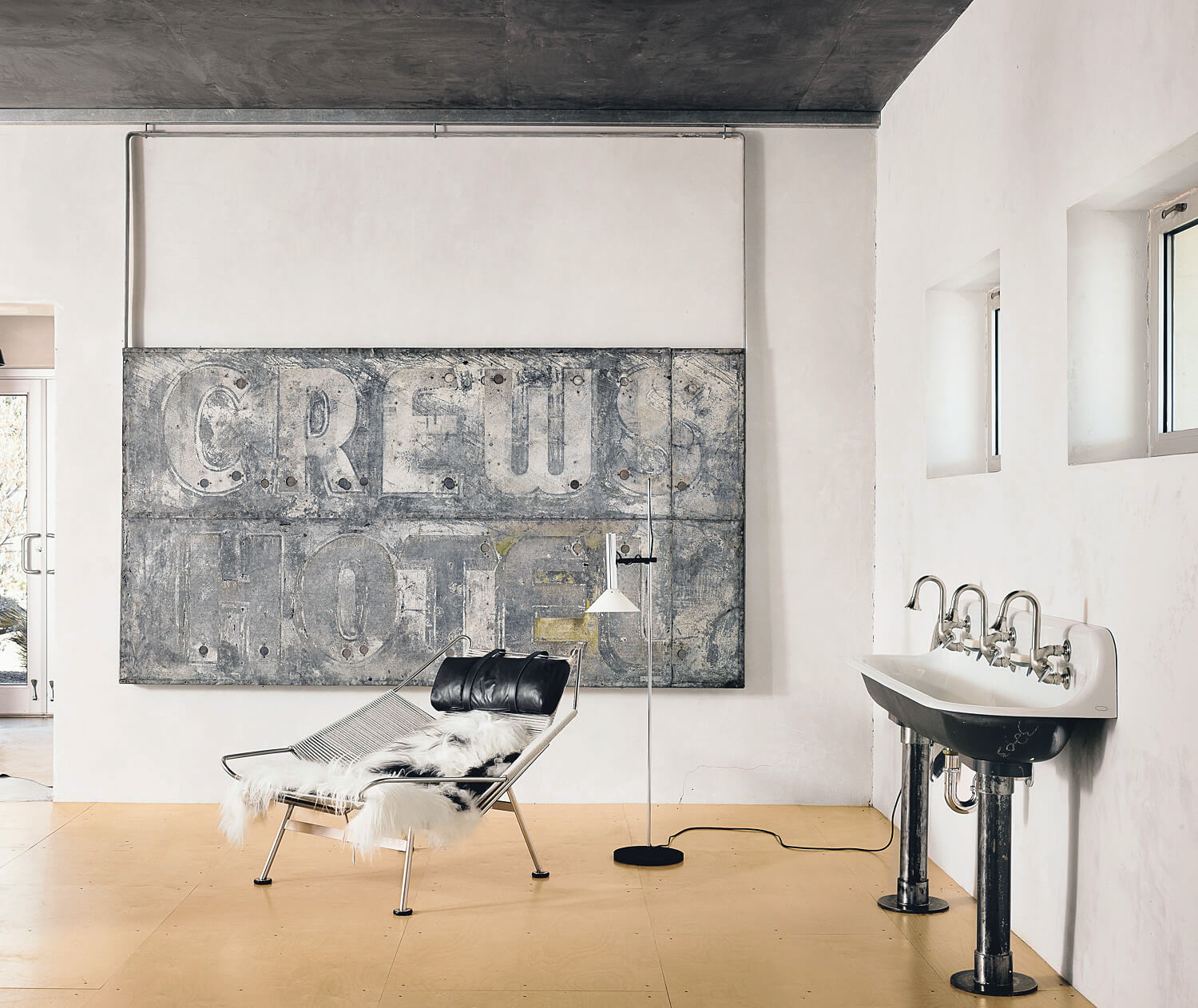 A vintage metal sign, modern furniture and industrial sink in the bright, sleek space create an entirely modern vignette. A vintage metal sign, modern furniture and industrial sink in the bright, sleek space create an entirely modern vignette.