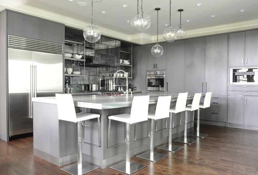 Glazed oak cabinets in a warm gray hide a lot of the workings of this Atlanta kitchen, allowing the countertops to stay uncluttered. Kitchen designer Kelly Carlisle also designed a clever backsplash with oxidized metal tiles to reflect light.