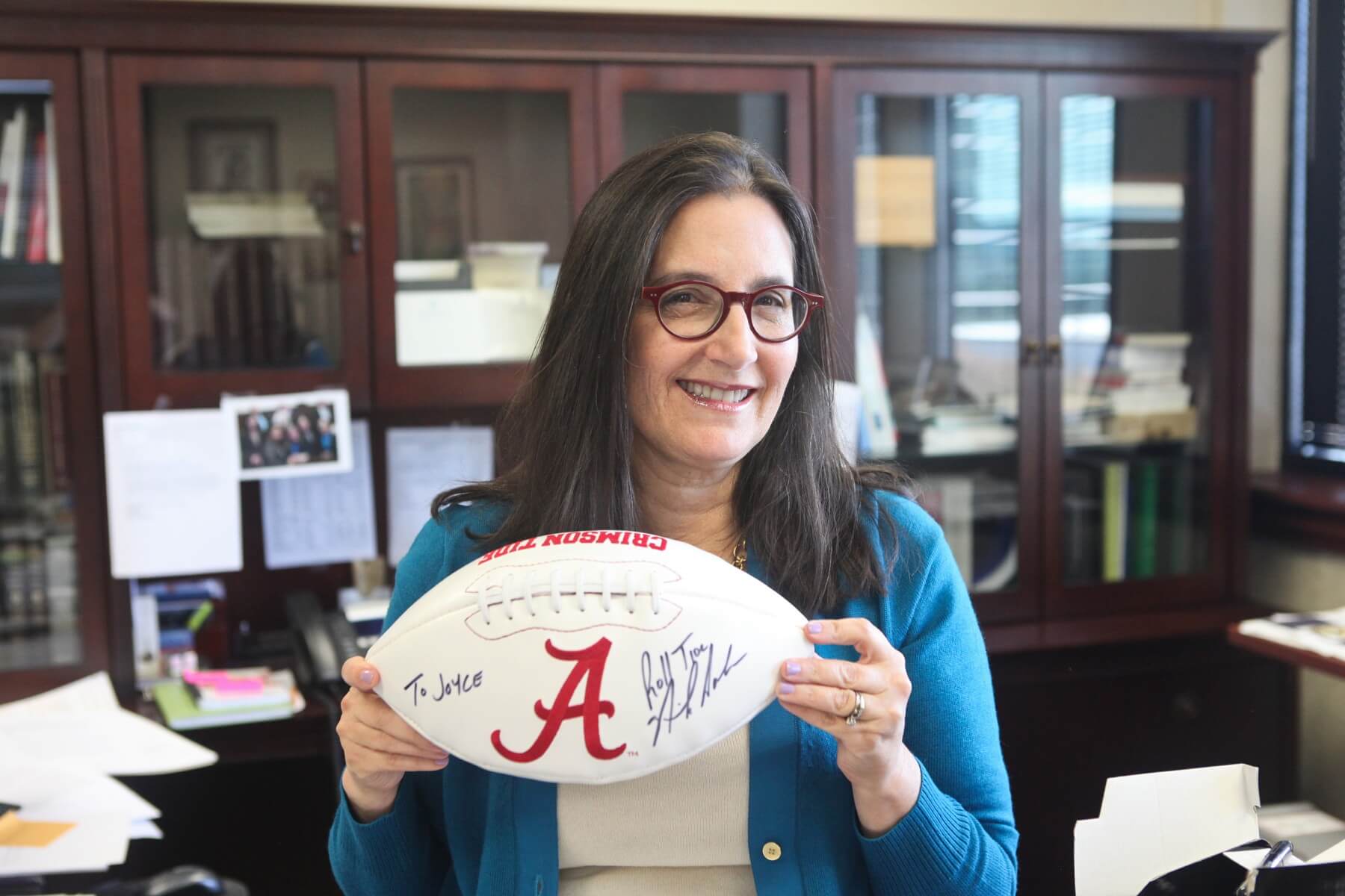 Joyce proudly displays her football autographed by Coach Saban. Joyce proudly displays her football autographed by Coach Saban.