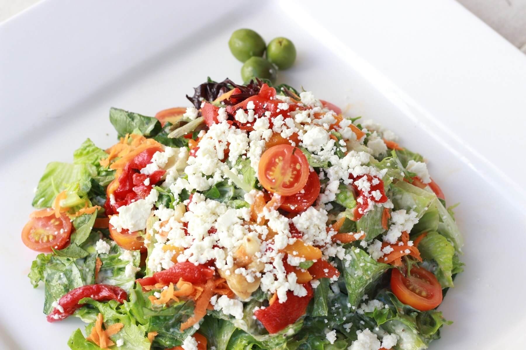 The Greek salad includes organic greens with feta, roasted garlic, bell peppers, tomatoes, kalamata olives, onions and creamy Greek dressing. The Greek salad includes organic greens with feta, roasted garlic, bell peppers, tomatoes, kalamata olives, onions and creamy Greek dressing.