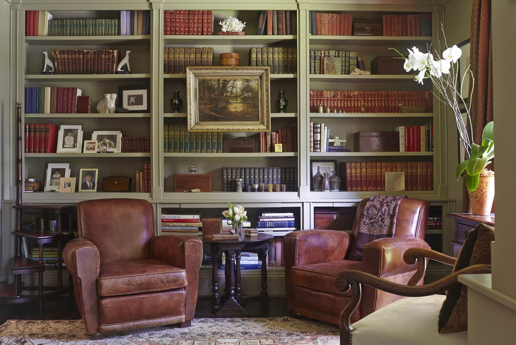 The study incorporates antique French club chairs, library steps from the homeowner's uncle's estate, and a library accented by personal collections of horn cups, boxes and books.