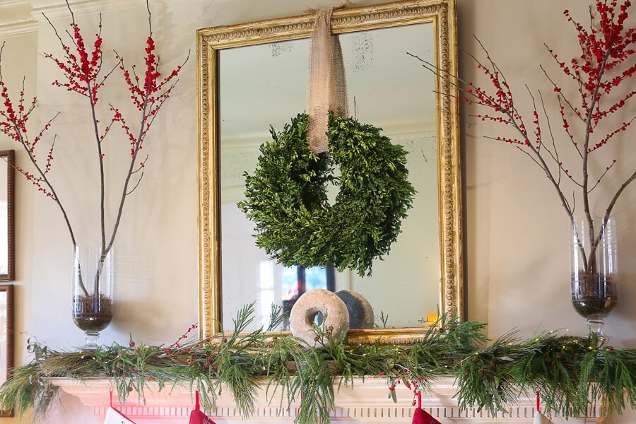 If you look closely at this mantle, what makes it appealing is its simplicity. Leigh used her existing vases and added seasonal red berries. The boxwood wreath can be found at local Christmas tree lots with ribbon from floral shops. The garland was cut from Leigh's backyard.
