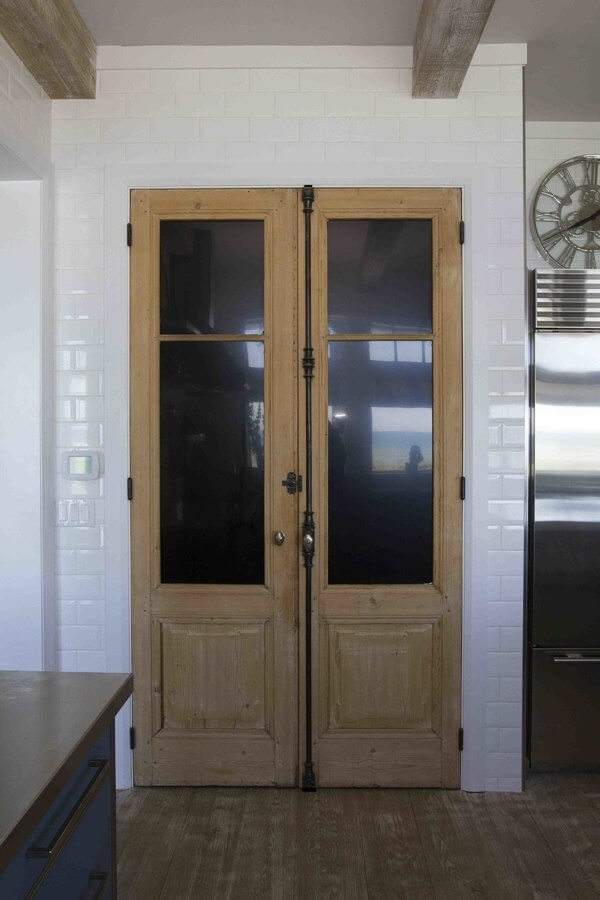 White subway tiles run floor to ceiling as a modern touch, joined by another set of European doors adding aged charm as the entrance to the pantry.