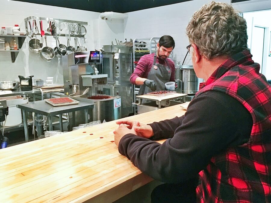 Man watching food prep from a counter overlooking retaurant kitchen