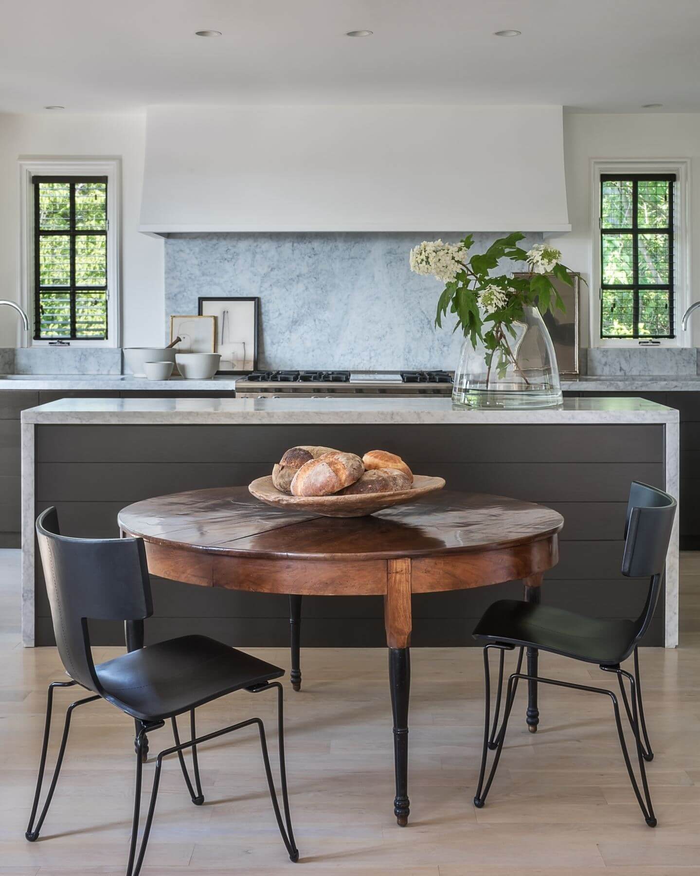 The sleek and elegant kitchen features a 19th Century French walnut dining table and Anziano Chairs by Donghia. Image: Peter Vitale