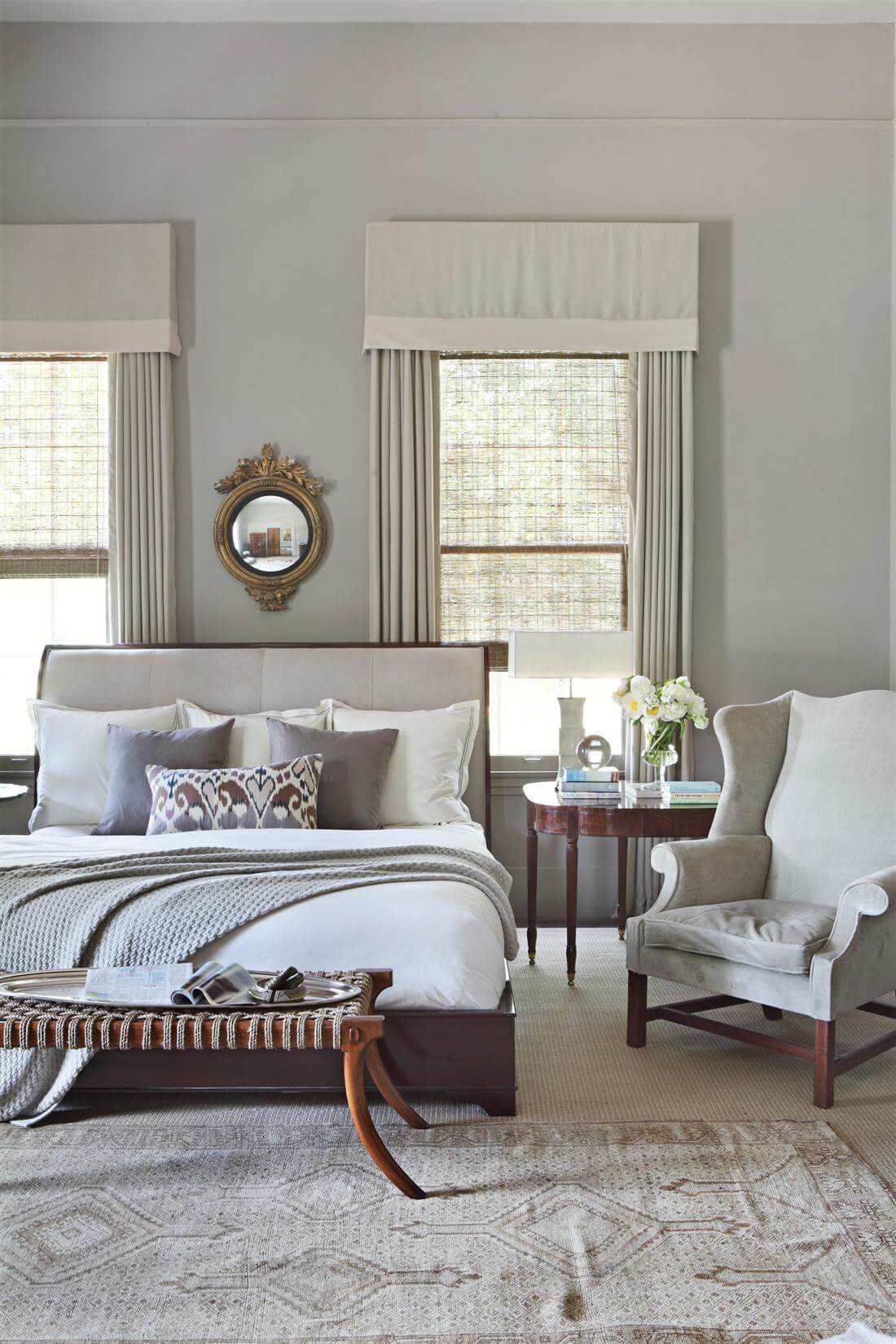 The master bedroom includes an upholstered sleigh bed, antique Georgian wing chair, saber leg ottoman by Formations, a bullseye mirror and an antique rug from Paige Albright Orientals. Image William Abranowicz