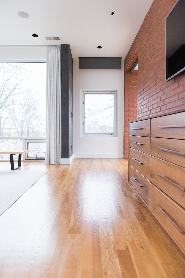 Looking outside onto the street, their dresser and television are along this exposed brick wall.