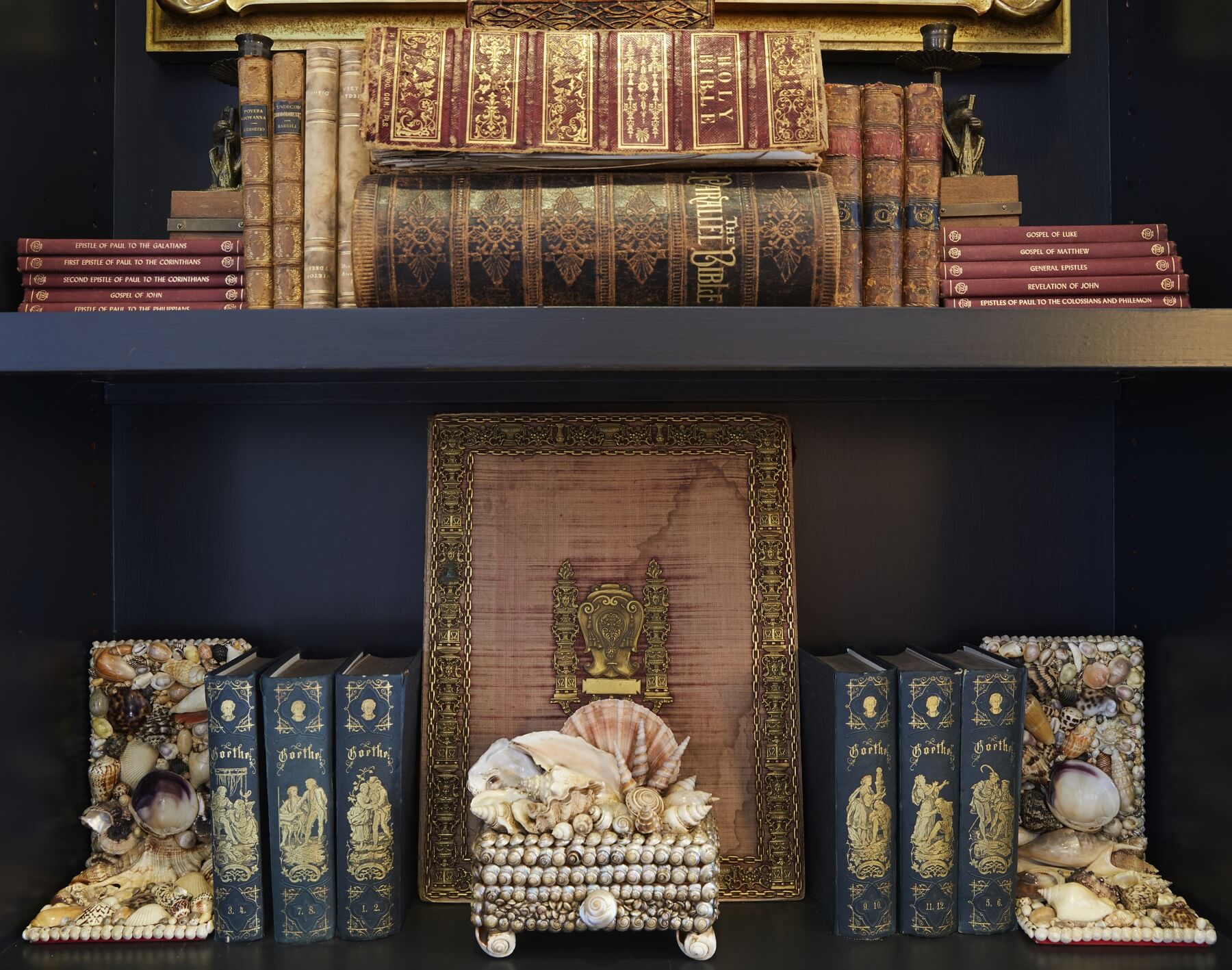 A closeup of the bookshelves reveals a beautiful arrangement of antique gilded Bibles, books and shell-adorned bookends and boxes. A closeup of the bookshelves reveals a beautiful arrangement of antique gilded Bibles, books and shell-adorned bookends and boxes.