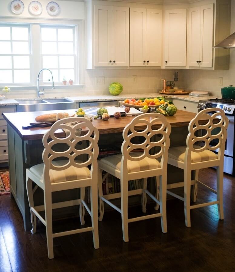Kitchen cabinets wear a coat of Benjamin Moore’s “Revere Pewter” on perimeter cabinets and “Antique Pewter” on the island to lighten up the room. Maggie asked the previous owner if she could keep these barstools with the house, then painted them white and added her own new fabric.
