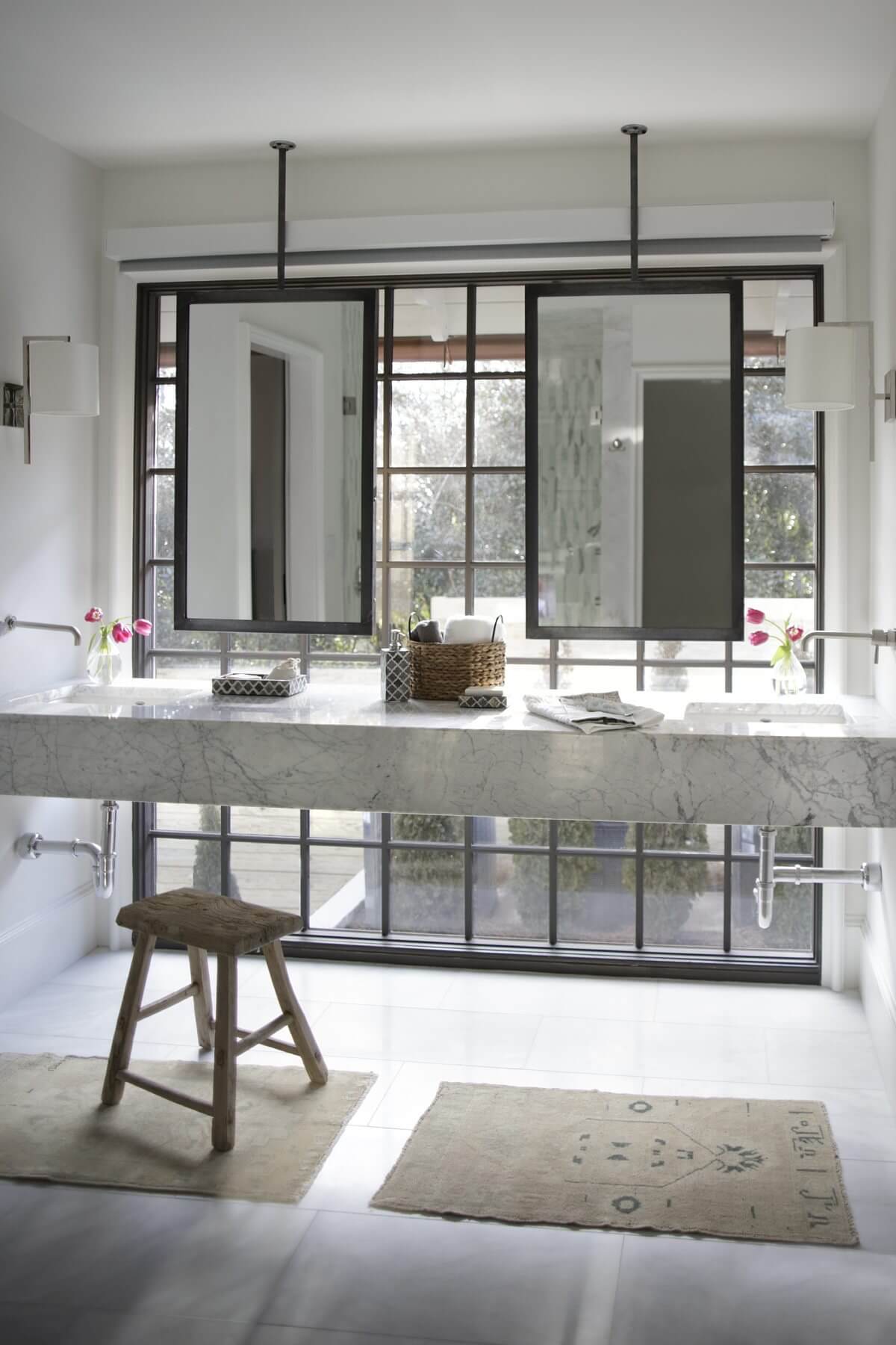 This gorgeous his-and-hers bathroom features natural light, marble, chic hardware and suspended mirrors. This gorgeous his-and-hers bathroom features natural light, marble, chic hardware and suspended mirrors.